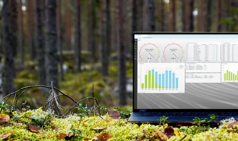A laptop computer displaying Monitor ERP sitting on top of a moss covered ground surrounded by trees.