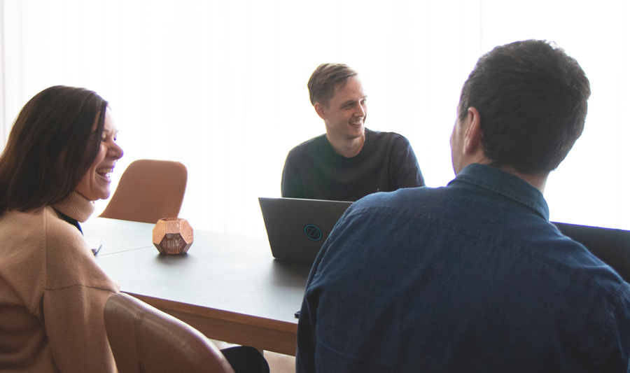 A group of people sitting around a table with laptops.