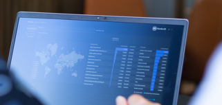 A person sitting in front of a laptop computer with Monitor BI (business intelligence) dashboards. 