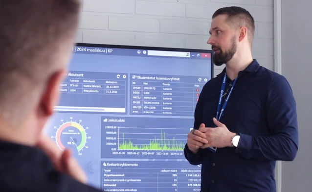 A man standing in front of a large screen displaying the ERP system Monitor ERP.