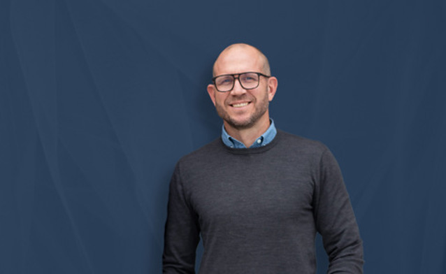 Johan Holmsten, global sales manager at Monitor ERP, standing infront of a blue background