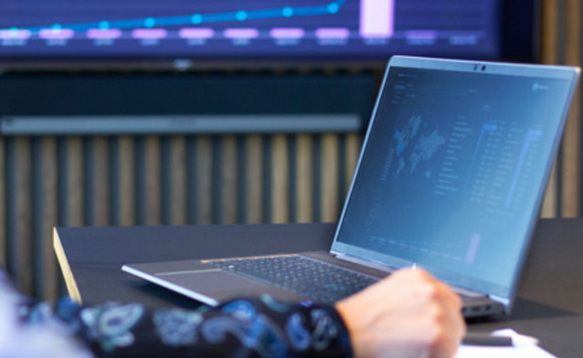 Laptop na stole i ekran w tle pokazujący system Monitor ERP