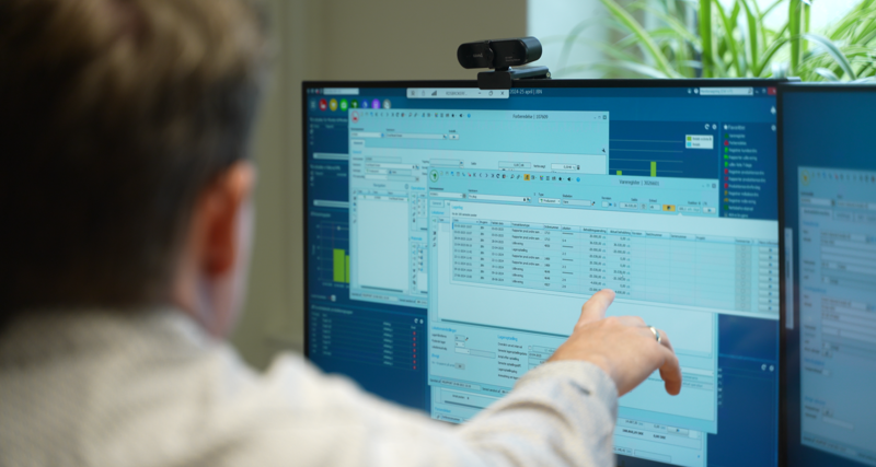 A person pointing at a computer with Monitor ERP dashboard on it.