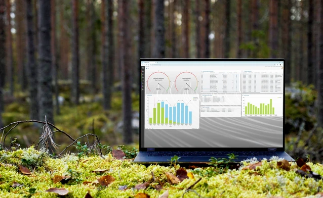 A laptop computer sitting on top of a moss covered field.