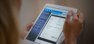 A woman is holding a tablet displaying a digital invoice. 