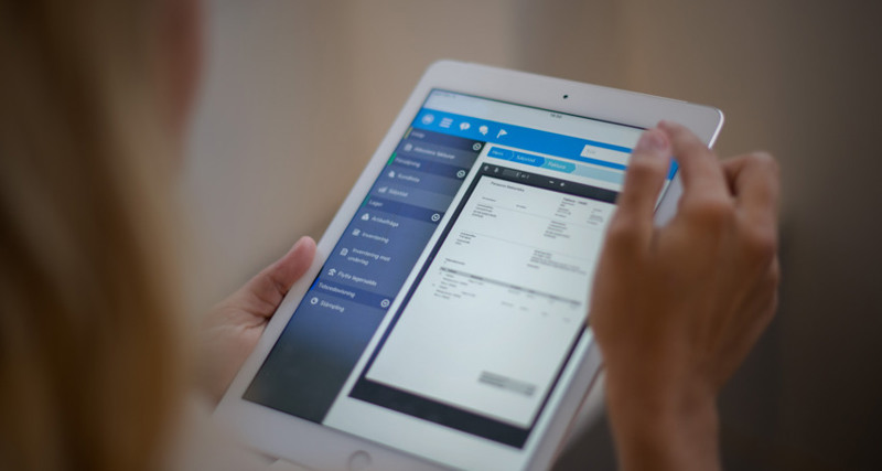 A woman is holding a tablet displaying a digital invoice. 