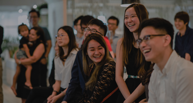 Personer sitter i grupp och skrattar tillsammans. 