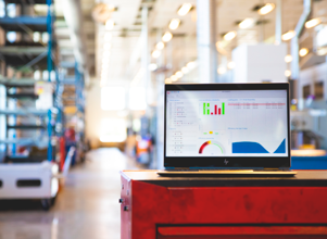Monitor ERP dashboard displayed on a laptop in a factory environment.