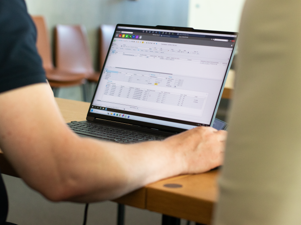 A person sitting at a table with a laptop displaying Monitor ERP features.