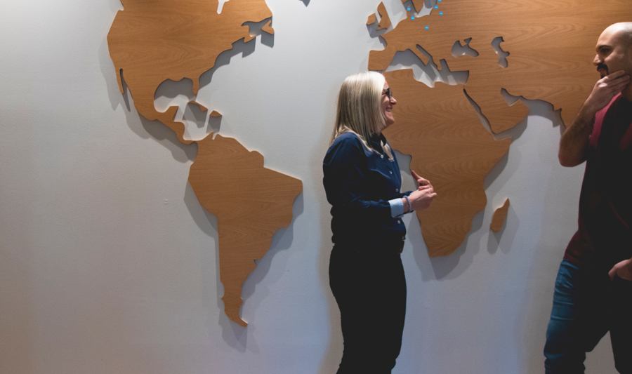 Två personer som arbetar på Monitor står och samtalar framför en stor karta som visar var vi finns. 