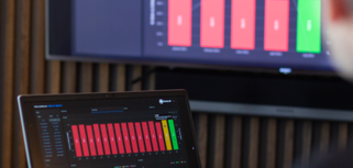 laptop on a table and a screen on a wall, showing Monitor ERP Dashboard