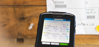 Person in a warehouse scanning pallet labels using a handheld scanner. 