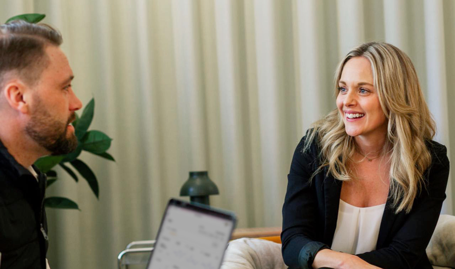 Tre personer sitter och samtalar. En person håller i en laptop som visar Boardeasers dashboard.