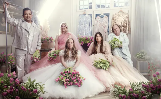 A group of people that are standing in front of flowers.